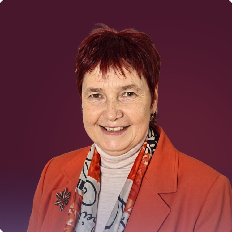 Svetlana Saksonova, portretfoto: sieviete ar īsiem sarkanbrūniem matiem, koraļļsarkanā žaketē un rakstainā šallē, plati smaida. Tumšsarkans fons.